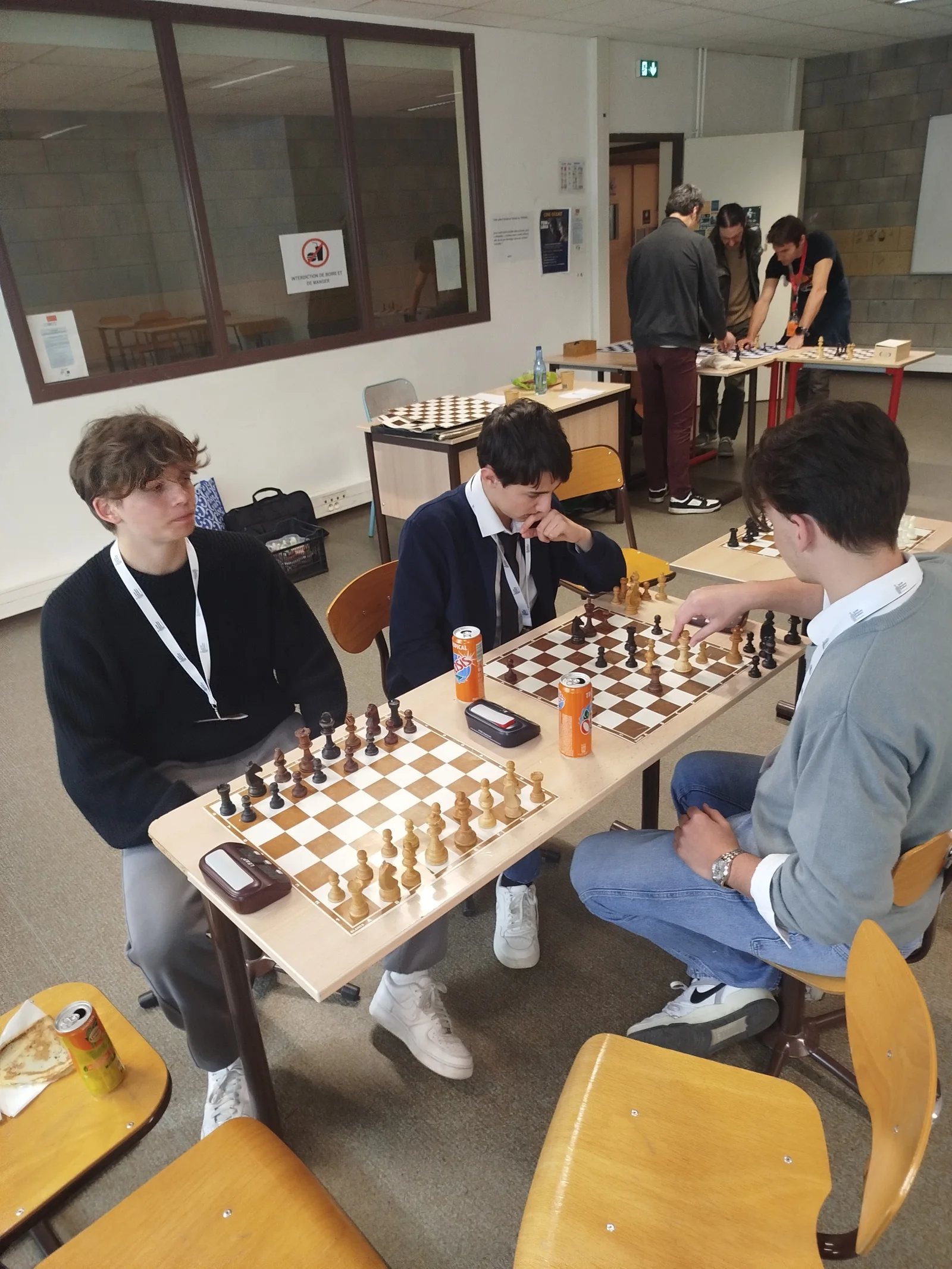 Plusieurs participants jouent aux échecs sur des tables dans une salle de classe.